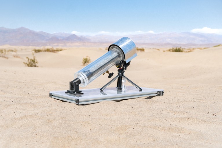 A small device with the appearance of a telescope laying in the sand of a dessert