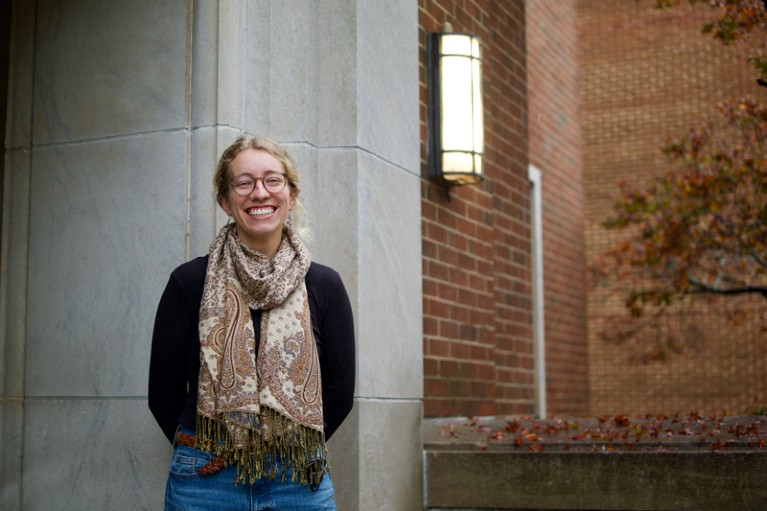 Portrait of Maryrose Weatherton standing in the doorway a large brick building